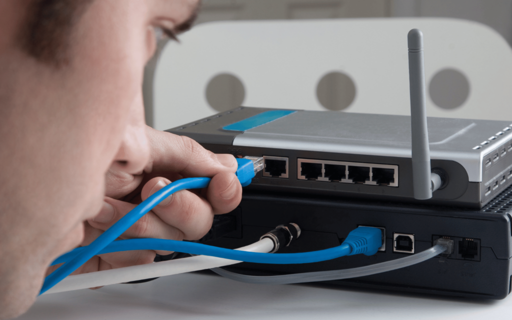 man plugs in network cable into router