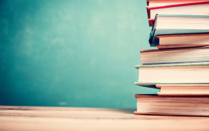 a stack of textbooks in front of a blackboard