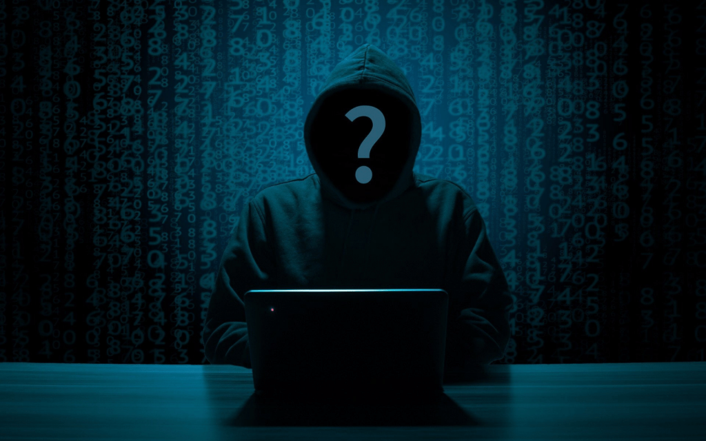 A hooded figure sits infront of a laptop, probably hacking Boeing